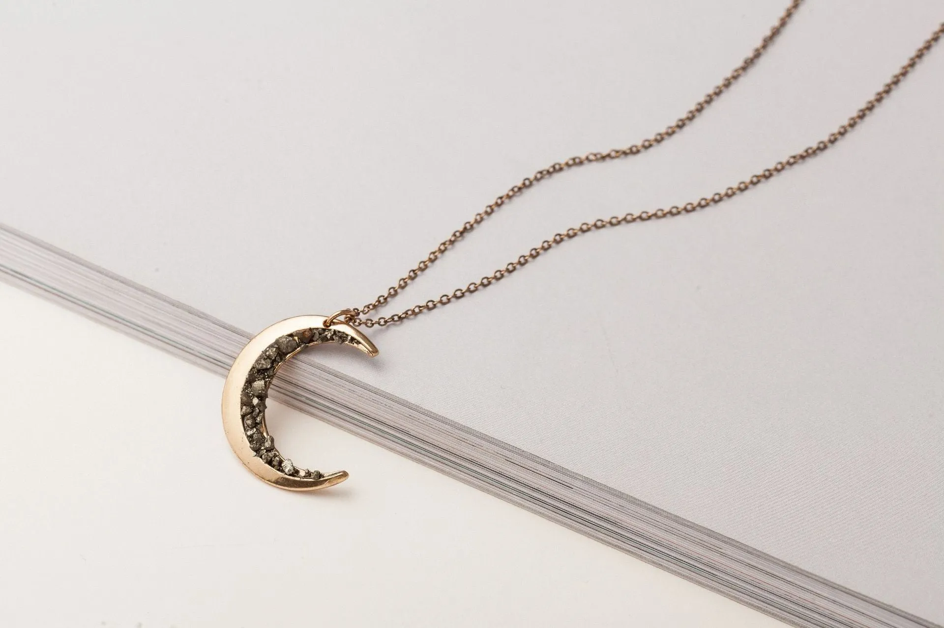 Irregular crescent moon necklace with diamonds and a snake bone chain.